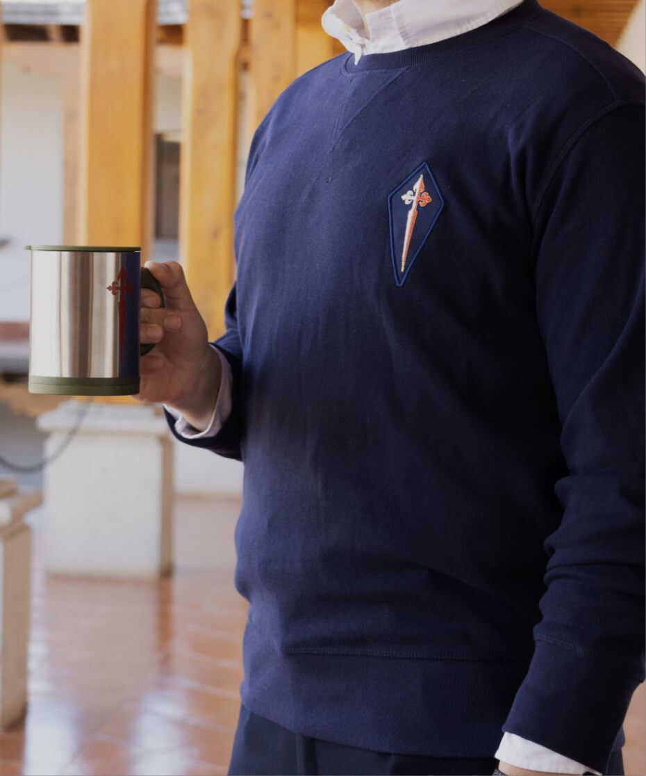 Hombre con camisa azul sosteniendo taza con diseño religioso.